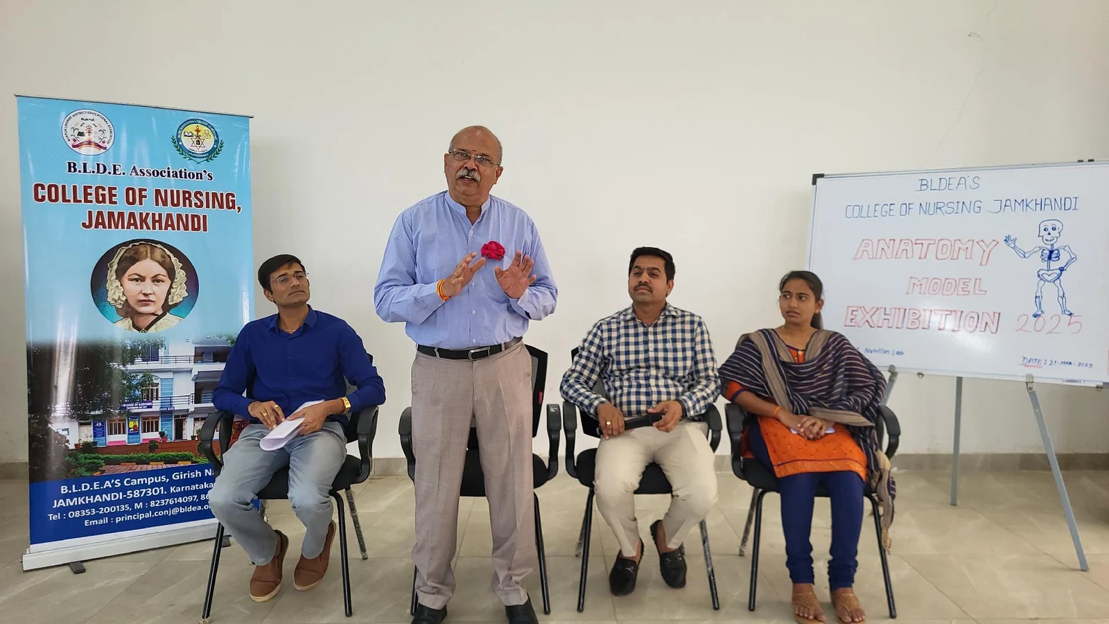 Dr Veeranna S Jatti Ayurvedic Physician Shri Vinayaka Ayurvedic Hospital Jamkhandi delivering appreciation speech at dais with BLDEAS College of Nursing Jamkhandi banner and Anatomy Model Exhibition board visible during closing ceremony March 21 2025