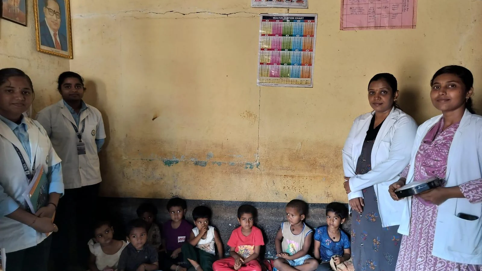 BLDEA College of Nursing Jamkhandi nursing students interacting with Anganwadi beneficiary children seated inside Anganwadi Centre Kakanawadi during Community Health Nursing educational visit learning early childhood care nutrition 2026