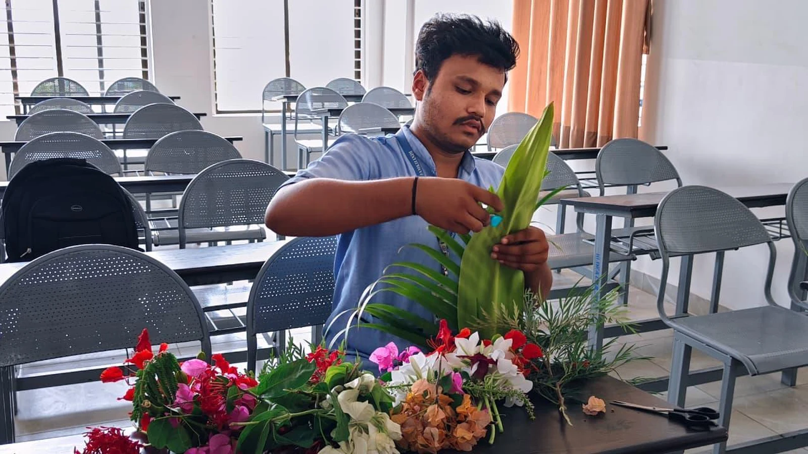 Male student arranging colourful bouquet at Intercollegiate Bouquet Making Competition 2026 – BLDEA College of Nursing Jamkhandi