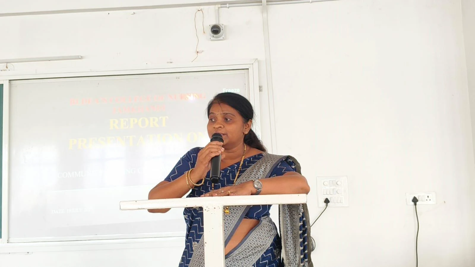 Prof Dr Sheela Kaddimani Chief Guest Department of Community Health Nursing Gopala Gowda Shathaveri Memorial College of Nursing Mysore addressing students at Community Health Nursing Report Presentation BLDEAS College of Nursing Jamkhandi July 19 2025 with Report Presentation projector screen behind