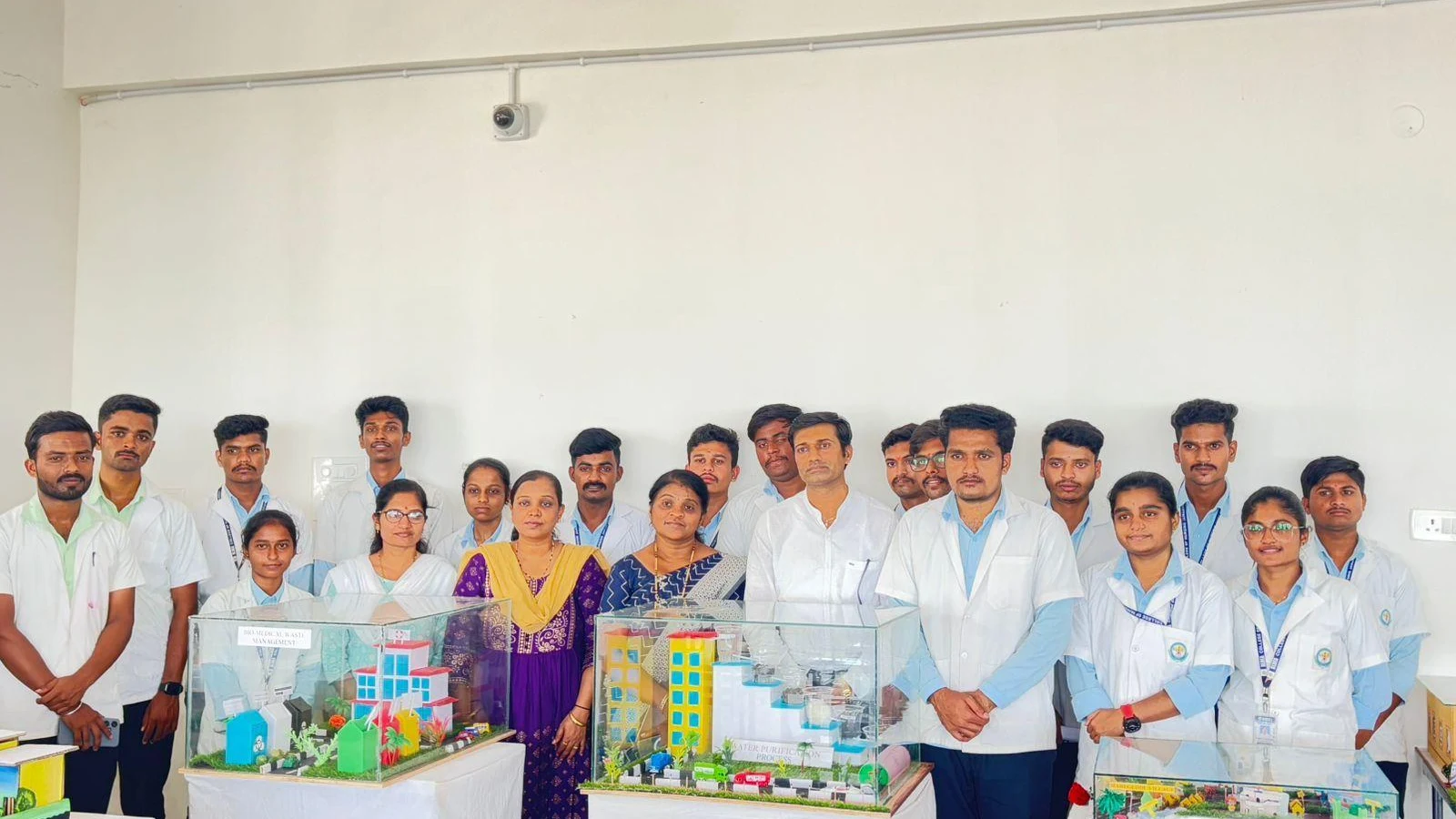 BSc Nursing students from BLDEAS College of Nursing Jamkhandi with community health models including scale models of hospitals and buildings displayed in glass showcases during Community Health Nursing Report Presentation for Mareguddi village posting July 19 2025