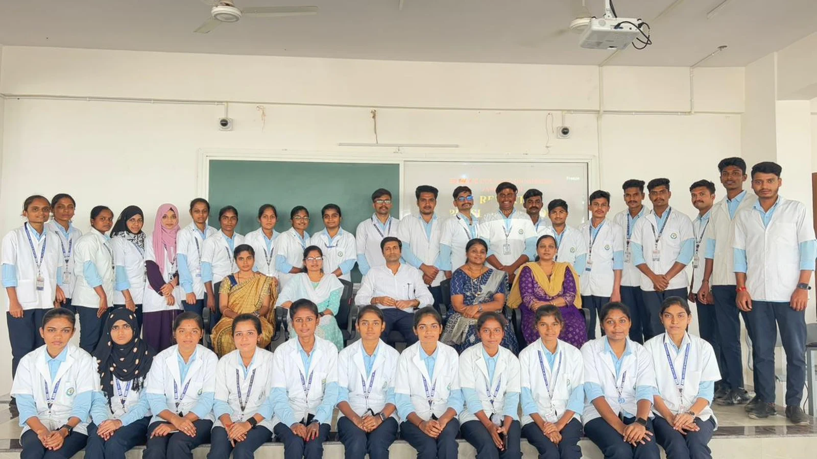 Group photo of Final Year and Fifth Semester BSc Nursing students and faculty of BLDEAS College of Nursing Jamkhandi who completed 15-day Community Health Nursing clinical posting at Mareguddi village gathered in seminar hall for report presentation July 19 2025 with Report Presentation text on projector screen