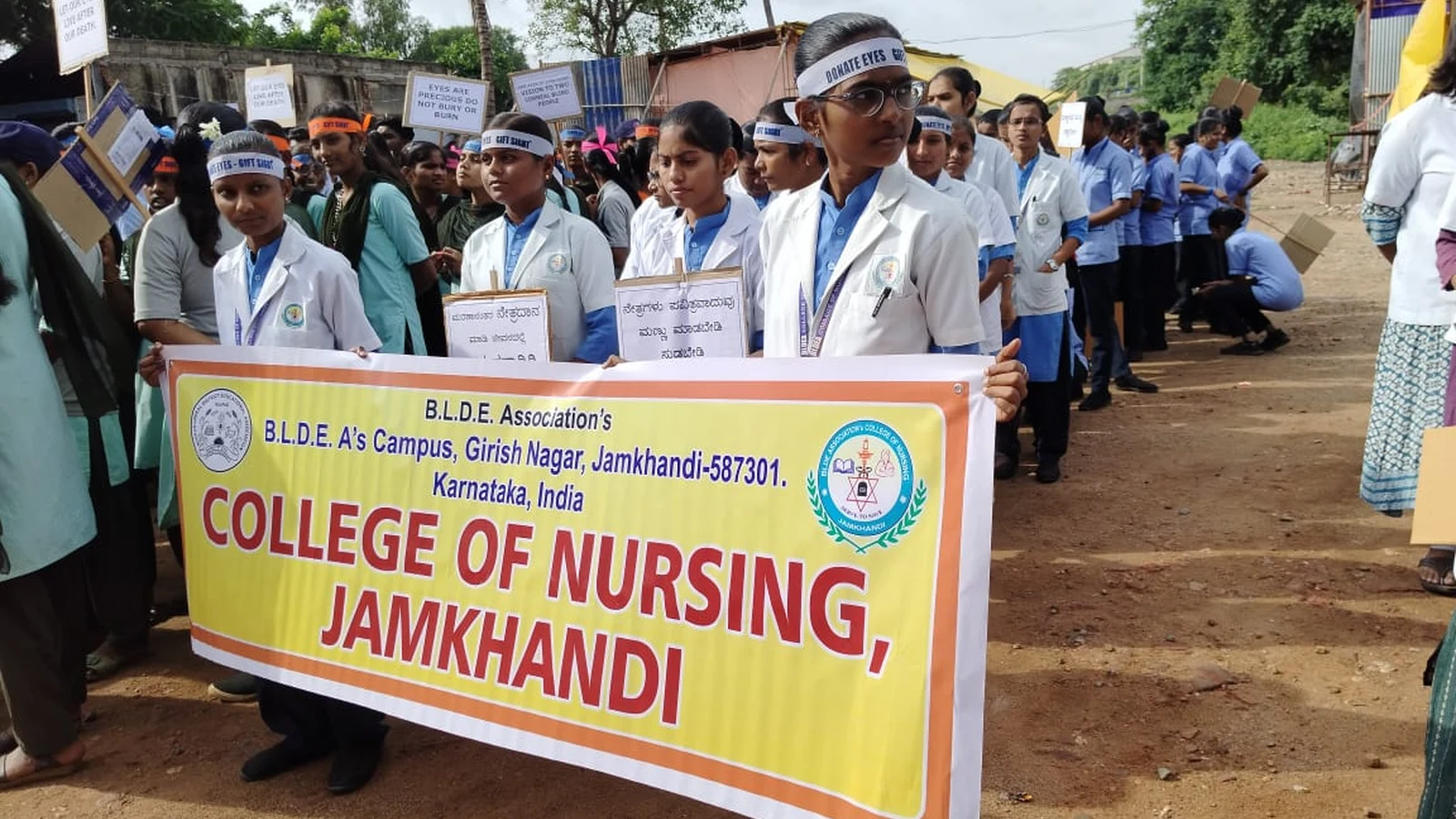 BLDEAS College of Nursing Jamkhandi students and staff in uniform marching with BLDEA Association College of Nursing Jamkhandi yellow banner during Eye Donation Awareness Rally National Eye Donation Week September 4 2024 Jamkhandi wearing headbands and carrying placards