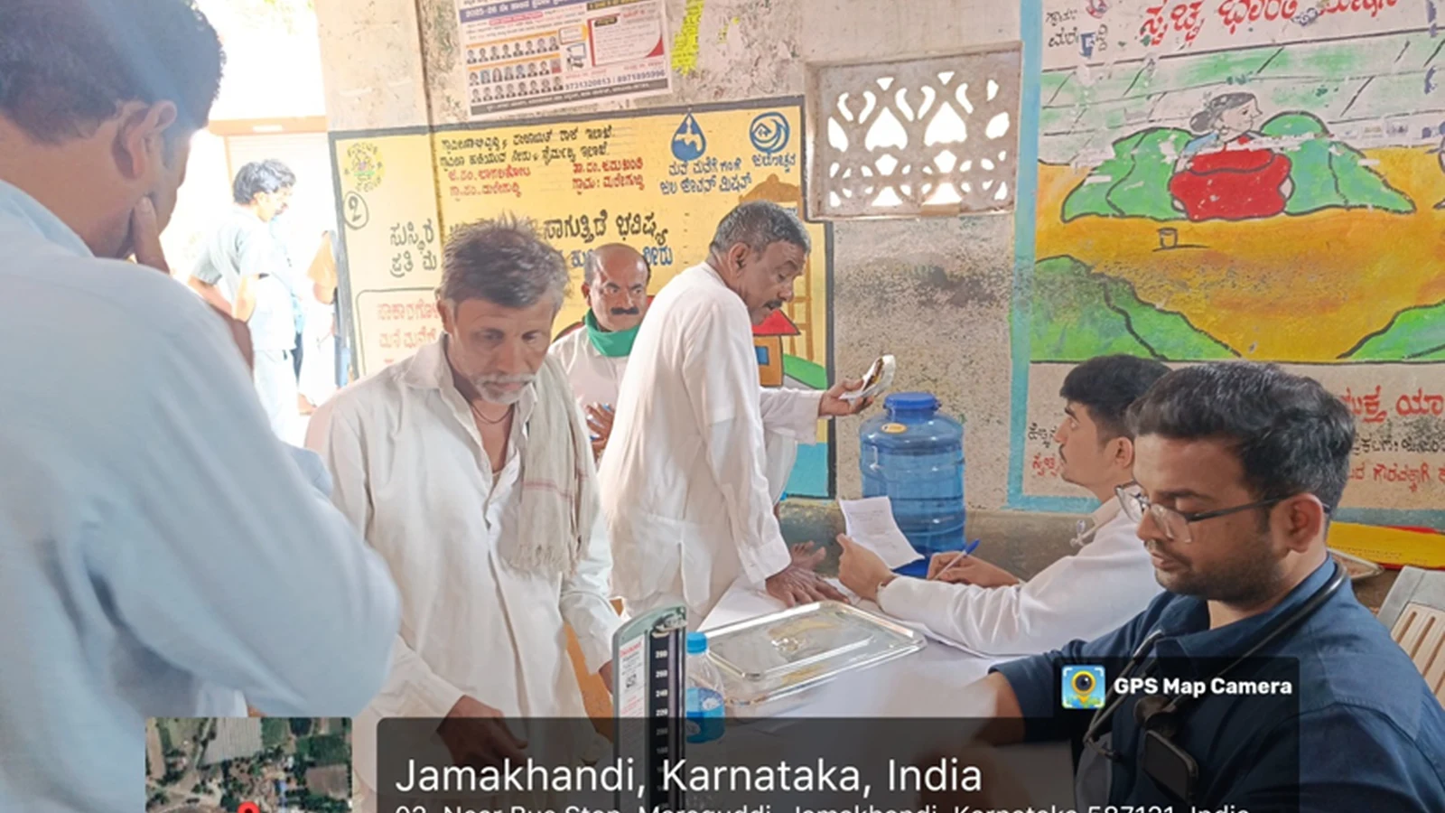Doctors and nursing students from BLDEAS College of Nursing Jamkhandi examining and attending to villagers queuing at free health check-up camp near bus stop Mareguddi village Karnataka with Kannada health awareness posters on wall August 1 2025