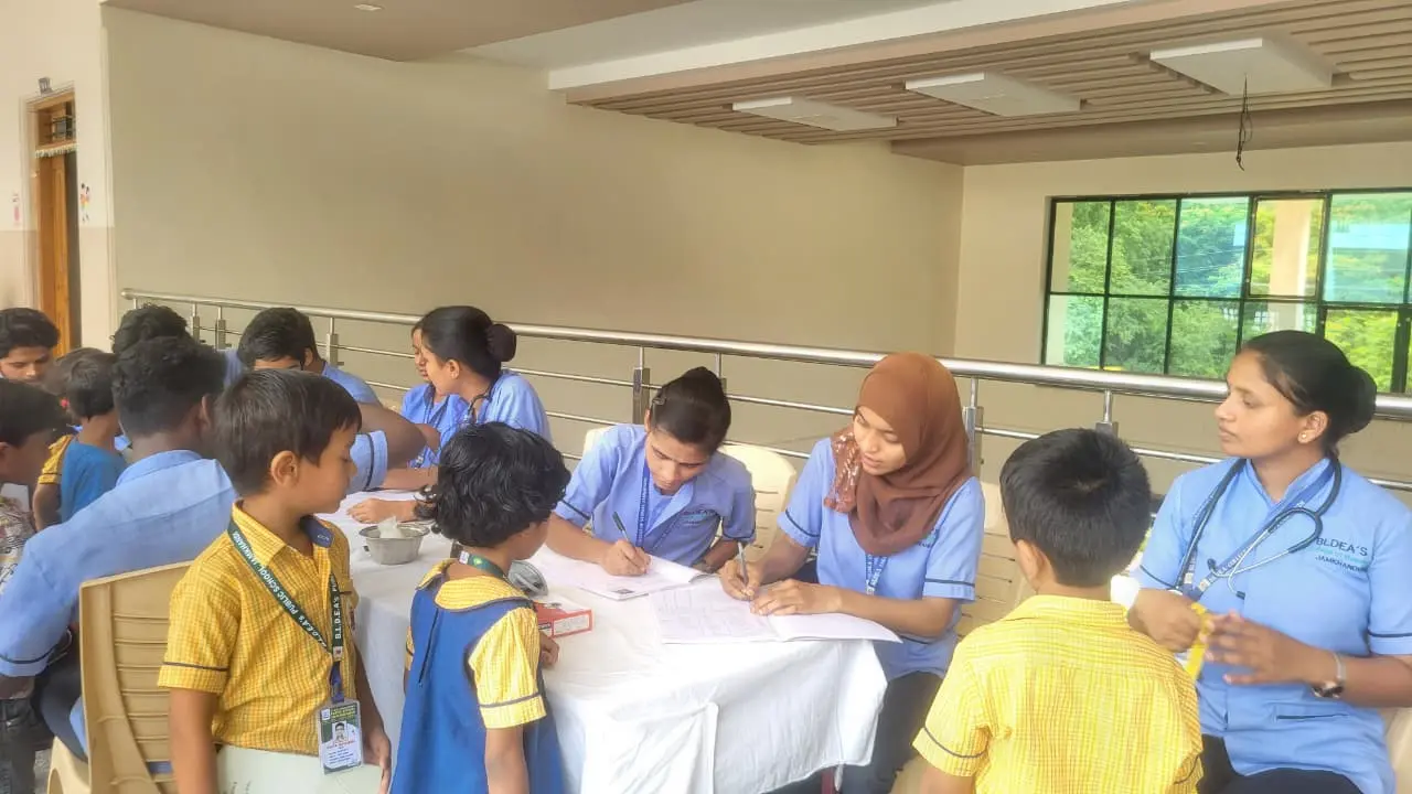 Nursing student measuring height and weight of school student during free health checkup camp Jamkhandi