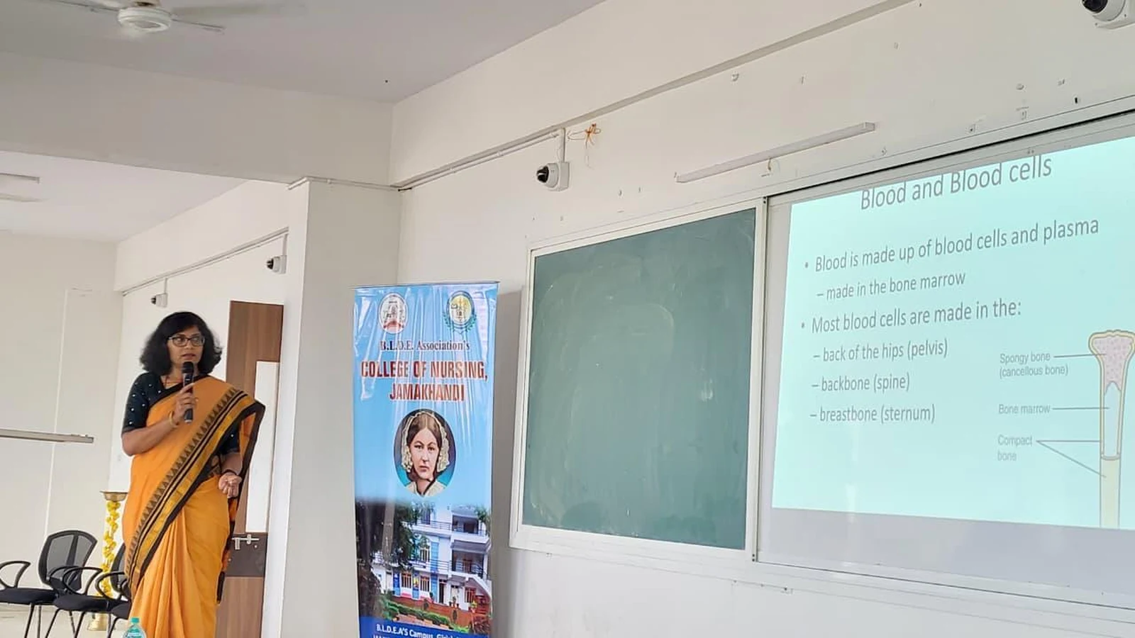 Dr Sangam Hebballi Consultant Haematologist presenting Blood and Blood Cells session at guest lecture on Blood Cancer Challenges Prevention and Nursing Responsibilities at BLDEA College of Nursing Jamkhandi with projector screen showing slide October 15 2025