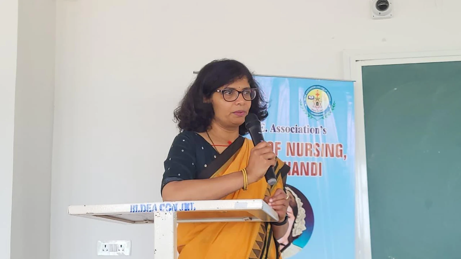 Dr Sangam Hebballi Consultant Haematologist Worcestershire Acute Hospitals NHS Trust UK speaking at lectern during guest lecture on Blood Cancer Challenges Prevention and Nursing Responsibilities at BLDEA College of Nursing Jamkhandi October 15 2025
