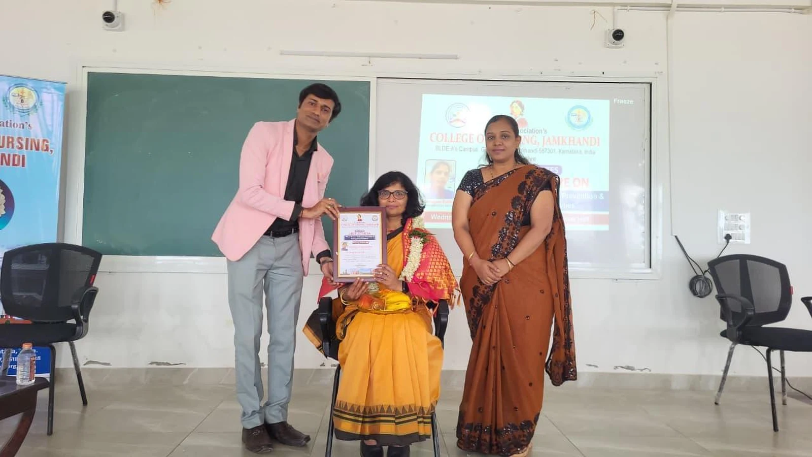 Faculty member presenting certificate of appreciation and memento to Dr Sangam Hebballi Consultant Haematologist at guest lecture on Blood Cancer Challenges Prevention and Nursing Responsibilities at BLDEA College of Nursing Jamkhandi October 15 2025
