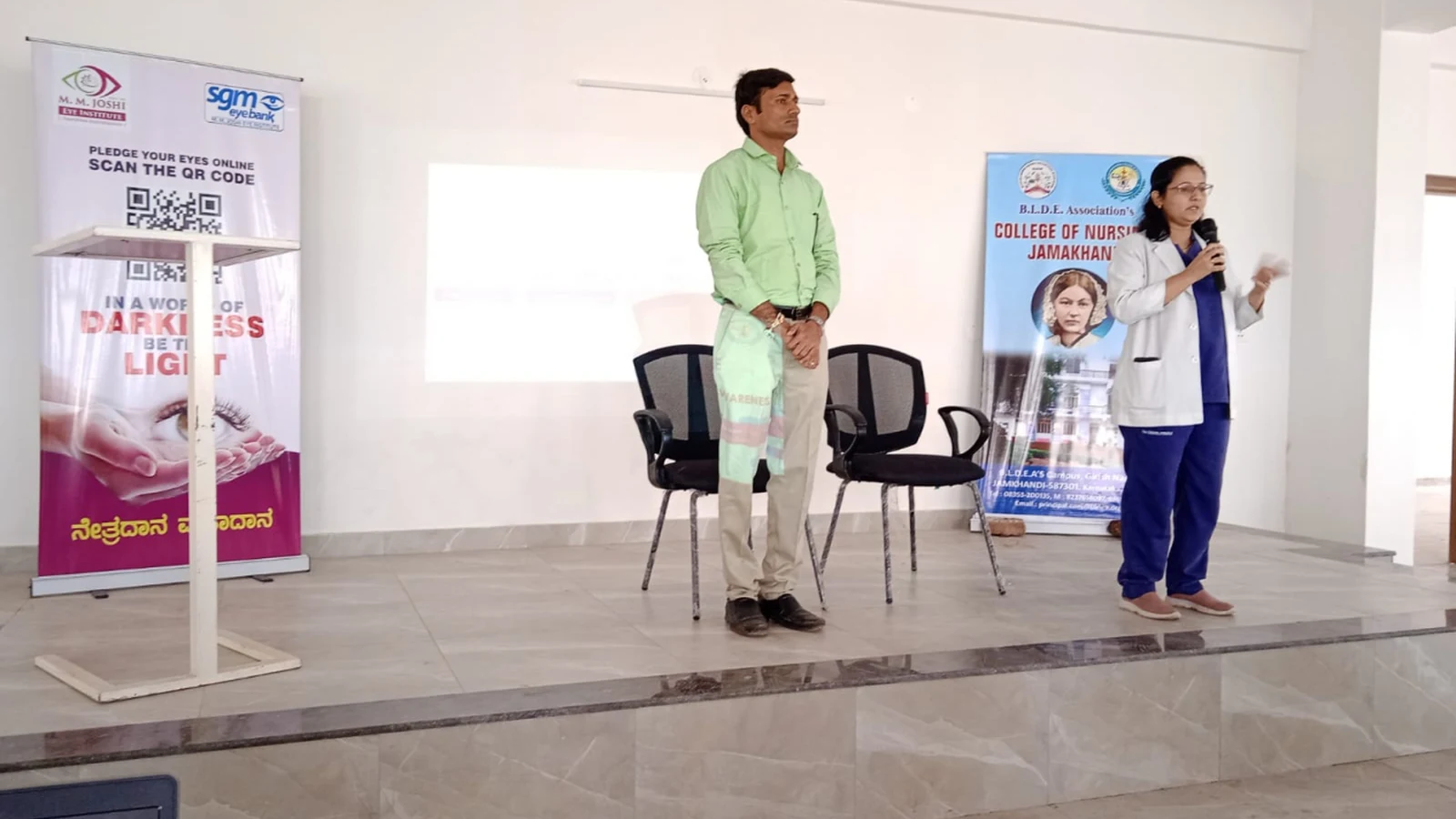 Mr Somesh Nikkam PG Nursing Tutor BLDEAS College of Nursing Jamkhandi standing on stage with student speaker at microphone during Guest Lecture on Eye Care and Eye Donation Awareness September 4 2024 Seminar Hall BLDEAS College of Nursing Jamkhandi with MM Joshi Eye Institute banner and BLDEAS College of Nursing rollup banner visible