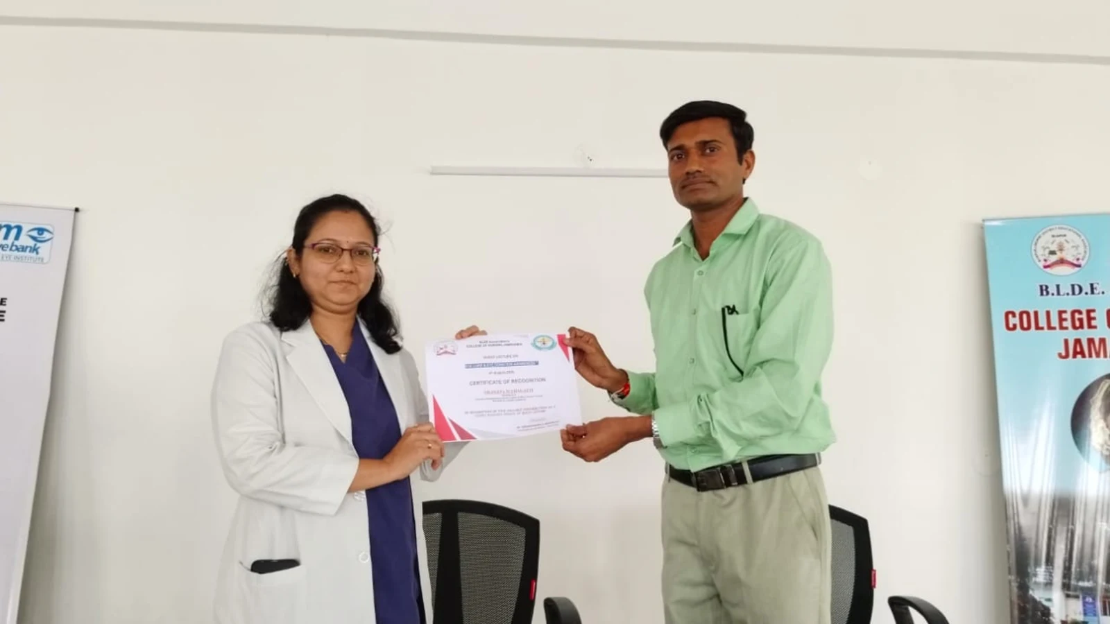 Dr Deepa Udagatti Consultant Ophthalmologist MM Joshi Eye Institute Jamkhandi receiving certificate of appreciation from Mr Somesh Nikkam PG Nursing Tutor at Guest Lecture on Eye Care and Eye Donation Awareness September 4 2024 BLDEAS College of Nursing Jamkhandi with BLDEAS College of Nursing Jamkhandi rollup banner visible