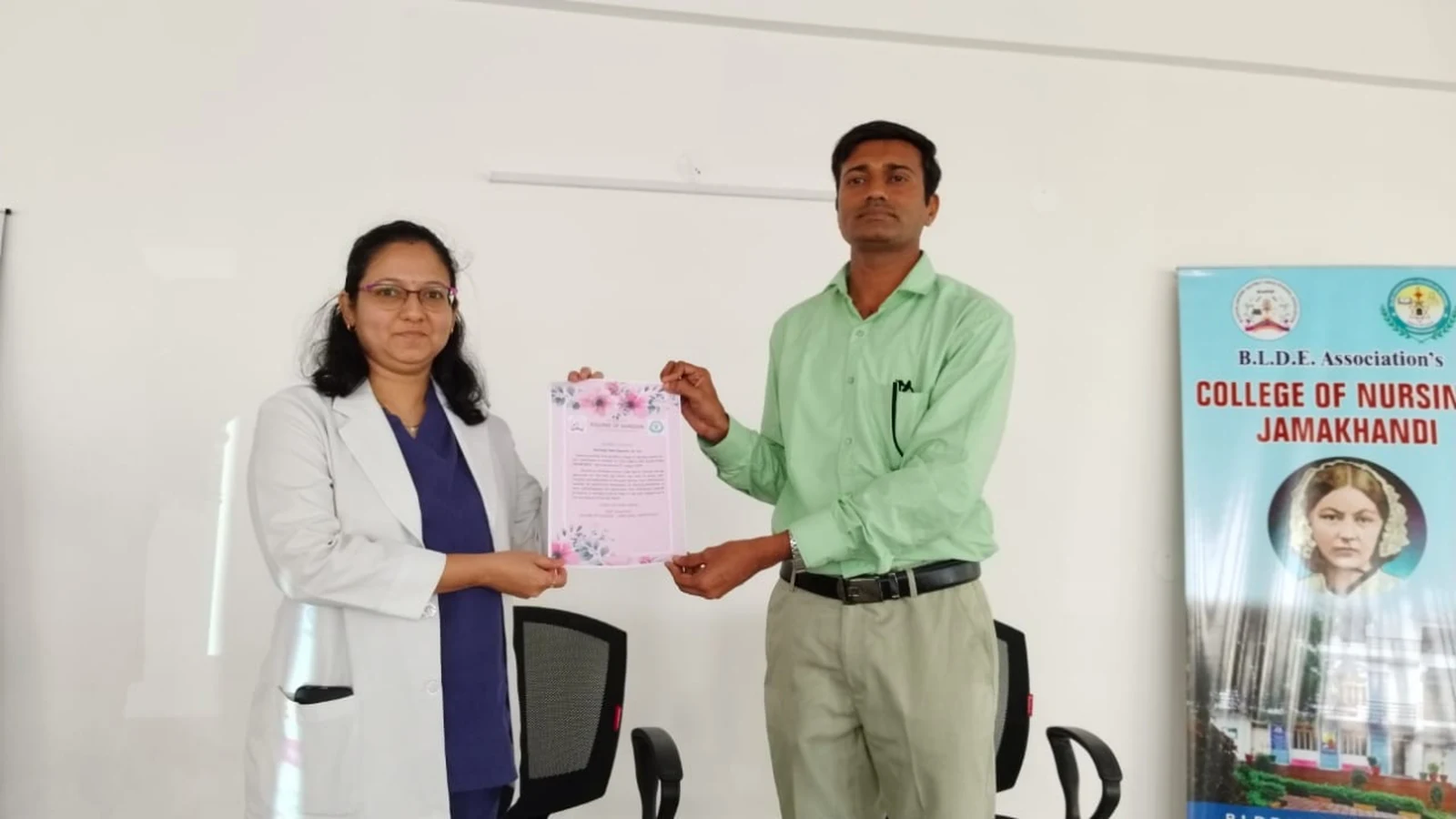 Dr Deepa Udagatti Consultant Ophthalmologist MM Joshi Eye Institute Jamkhandi receiving memento and appreciation letter from Mr Somesh Nikkam PG Nursing Tutor at Guest Lecture on Eye Care and Eye Donation Awareness September 4 2024 BLDEAS College of Nursing Jamkhandi with BLDEA Associations College of Nursing Jamkhandi rollup banner in background