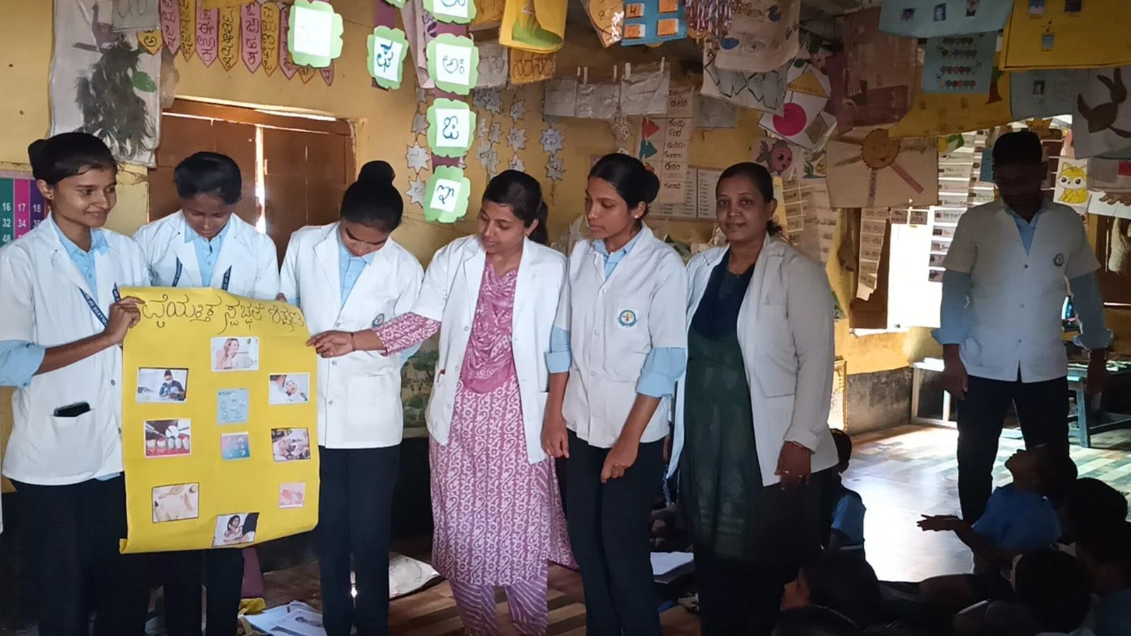 BLDEA College of Nursing Jamkhandi Seventh Semester BSc Nursing students with Mrs Shivaleela Sarawad conducting health education using charts and posters in classroom at Government Primary School Kakanwadi Village June 2026