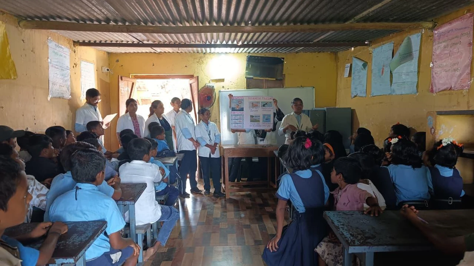 Seventh Semester BSc Nursing students BLDEA College of Nursing Jamkhandi presenting health education session with poster to school children seated in classroom at Government Primary School Kakanwadi Village June 2026