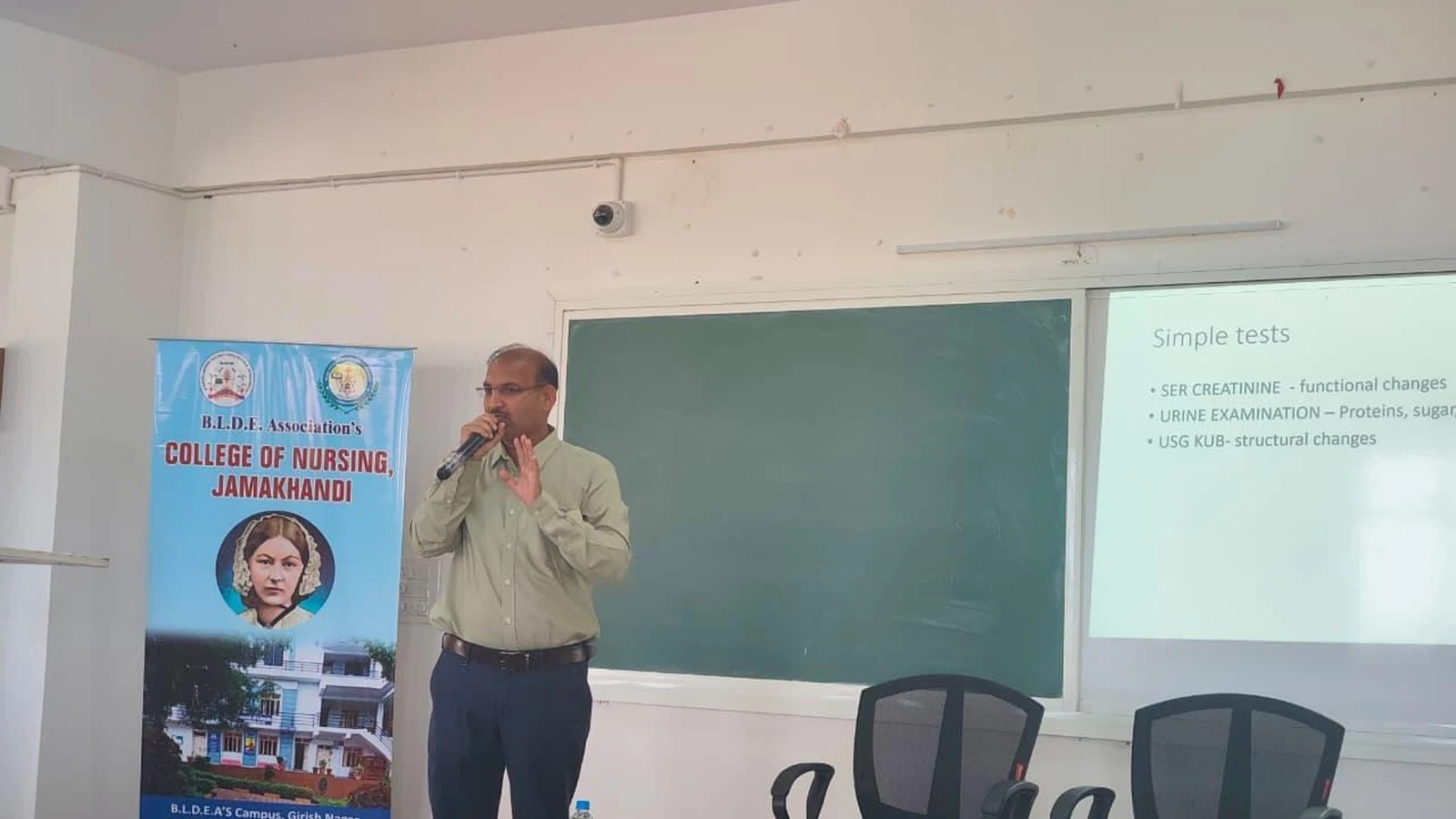 Dr. Basavaraj Ugran presenting slide on simple kidney tests including serum creatinine urine examination and USG KUB at BLDEA College of Nursing Jamkhandi