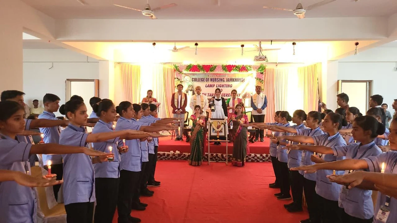 First Year BSc Nursing students taking Nursing Oath raising hands with candles at Lamp Lighting and Oath Taking Ceremony 2026 BLDEA College of Nursing Jamkhandi