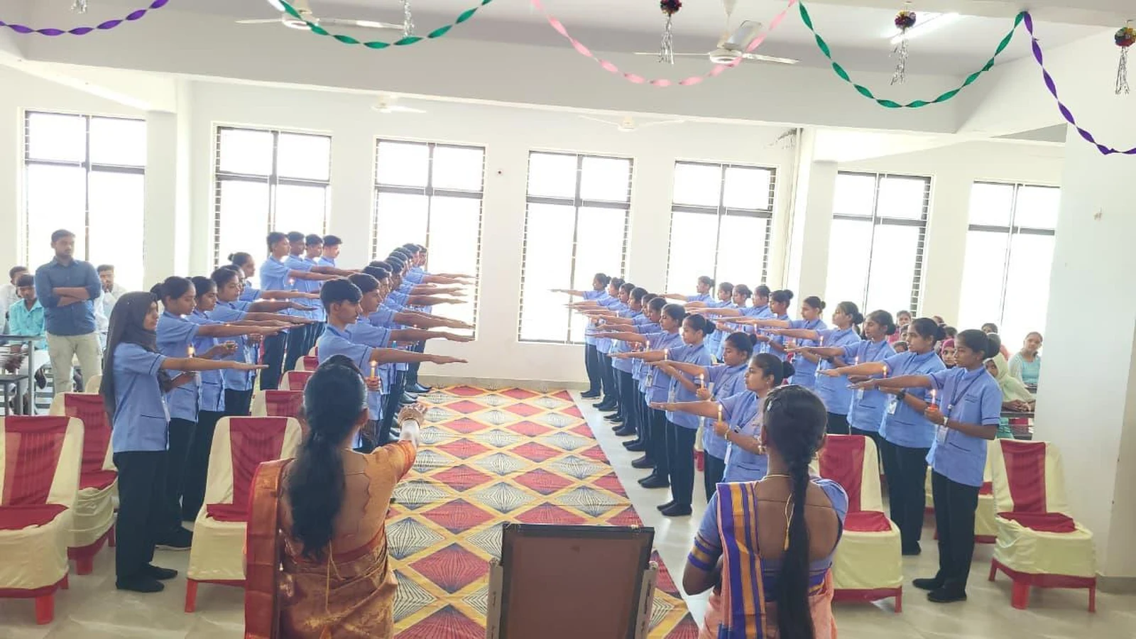 Wide view of Oath Taking Ceremony with nursing faculty administering oath to 4th Batch 1st Year BSc Nursing students holding candles in rows at BLDEA College of Nursing Jamkhandi October 25 2025