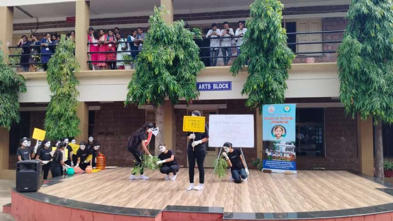 Second semester BSc Nursing students from BLDEAS College of Nursing Jamkhandi performing mime scene depicting importance of trees and environment during World Population Day 2024 program with students crouching with plants and holding TREE placard on stage at college campus Jamkhandi July 11 2024