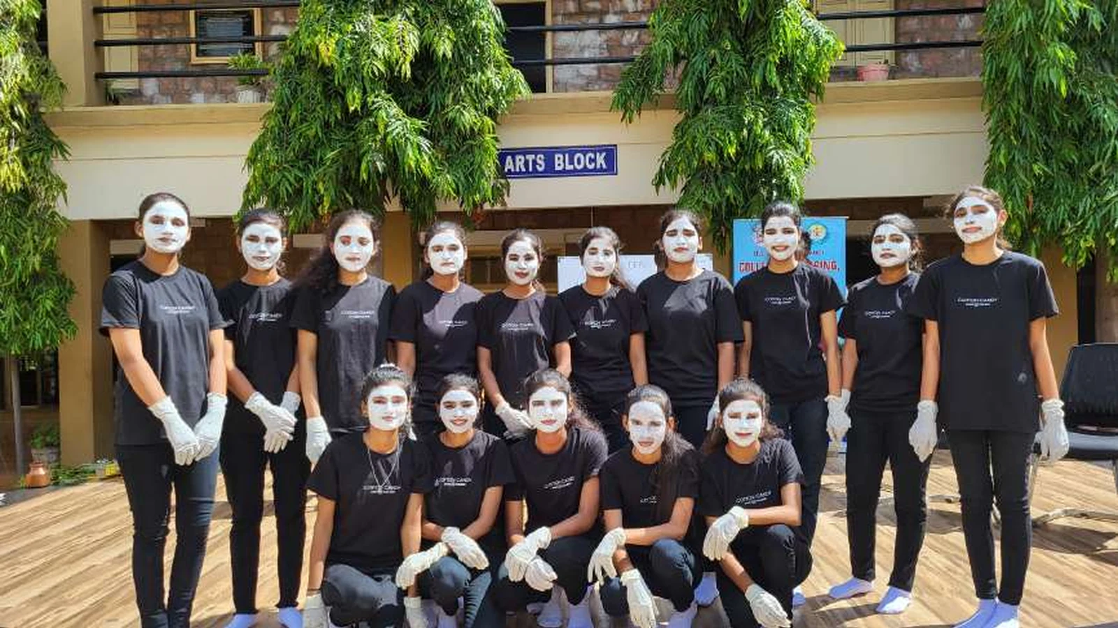 Group photo of sixteen second semester BSc Nursing students in black outfits with white face paint mime costume on stage in front of Arts Block building after World Population Day 2024 mime show at BLDEAS College of Nursing Jamkhandi July 11 2024
