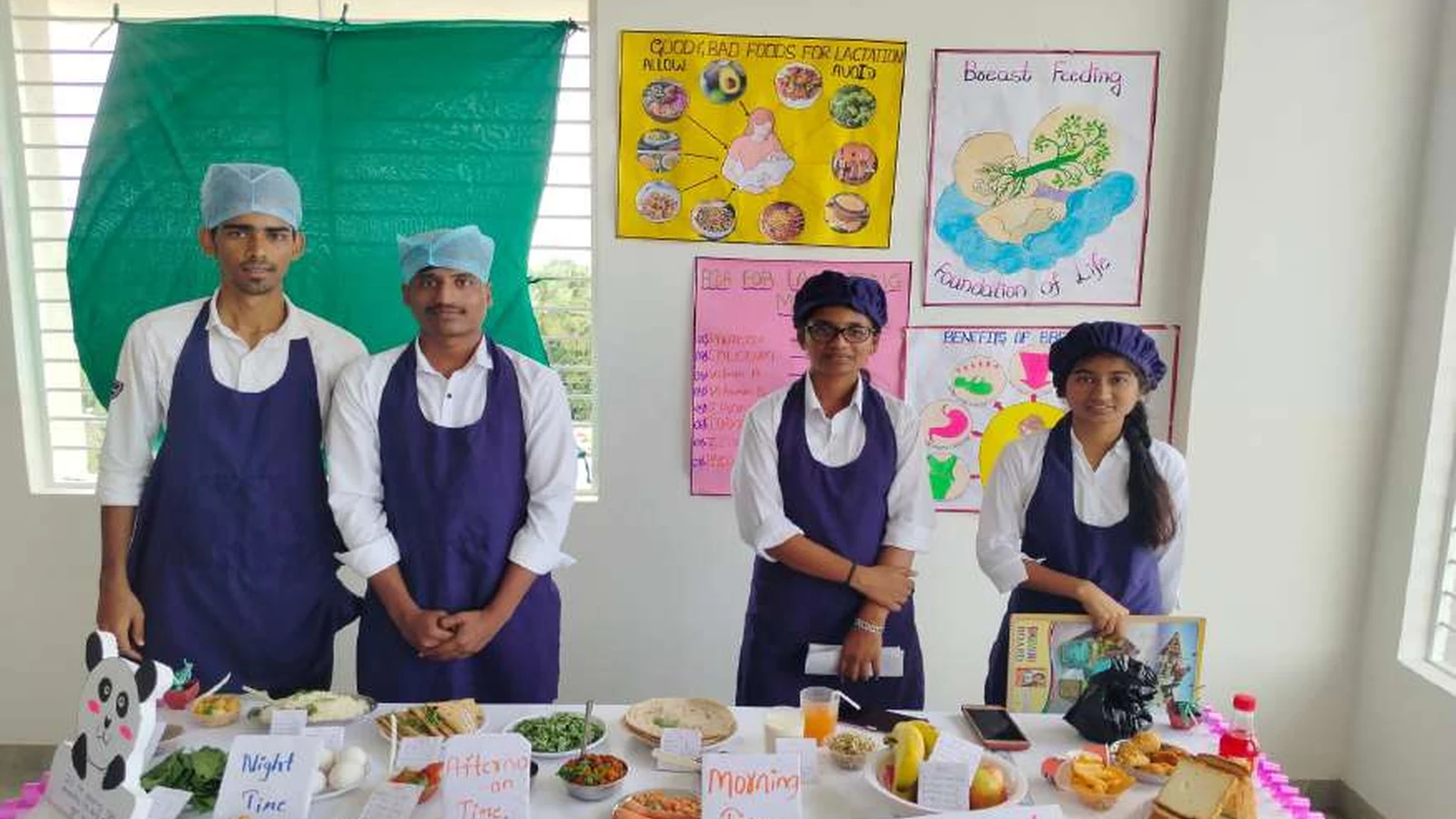 Second semester BSc Nursing students of BLDEAs College of Nursing Jamkhandi in blue aprons at their diet during lactation exhibition stall with Good Bad Foods for Lactation and Breastfeeding Foundation of Life posters on wall and Night Time Afternoon Time Morning Time Allow Food labeled food items on table during Nutrition Exhibition and Demonstration Programme 2024 at Nutrition Lab BLDEAs College of Nursing Jamkhandi September 11 2024