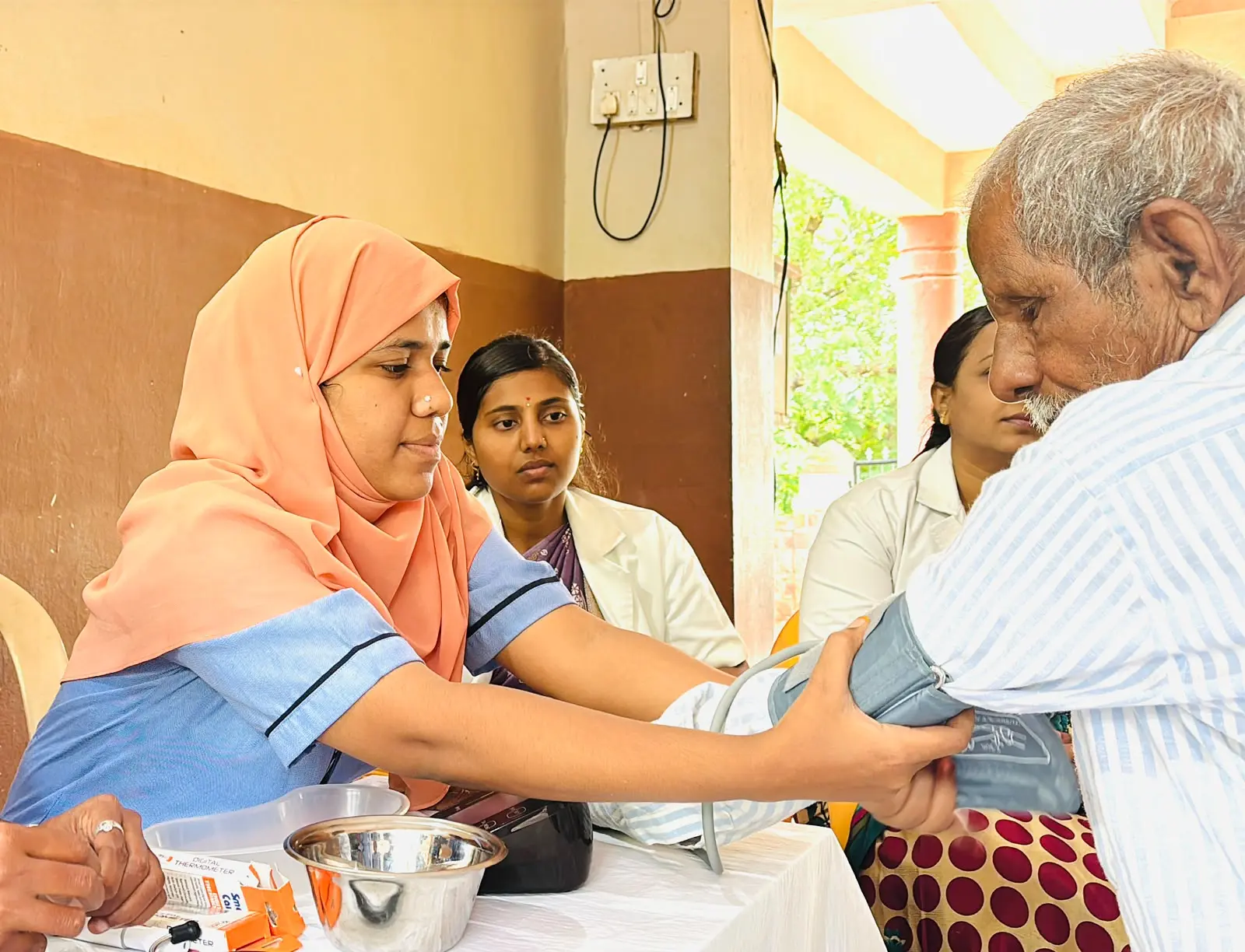 Seventh Semester B Sc Nursing students recording blood pressure of elderly resident during geriatric health screening camp Jain Vrudhrashram