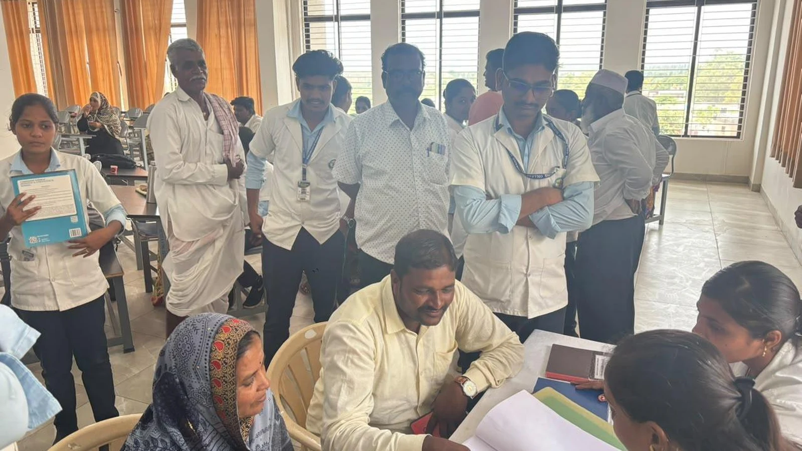 Faculty coordinator discussing student academic performance attendance and clinical competency records with parents at classroom table during interactive Parent-Teacher session BLDEA College of Nursing Jamkhandi June 2026