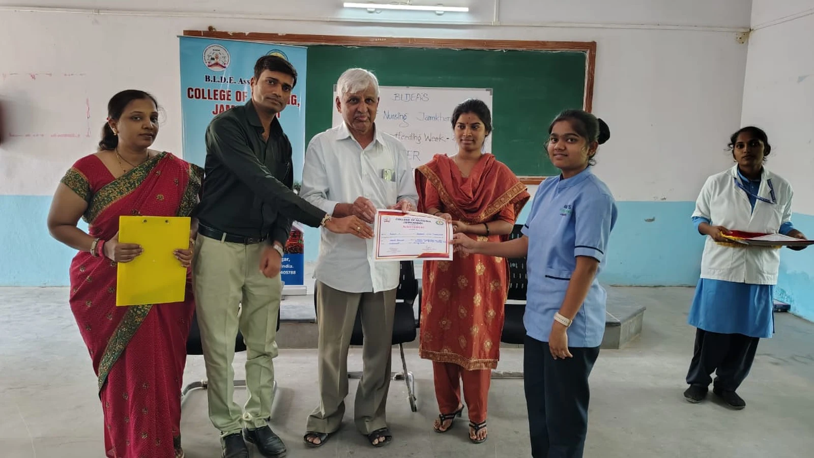 Dr H G Daddi Cardiologist Daddi Hospital Jamkhandi distributing prize certificate to winner BSc Nursing student at World Breastfeeding Week Poster Competition award ceremony BLDEAS College of Nursing Jamkhandi August 7 2024