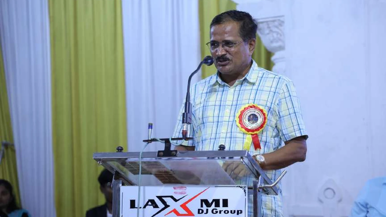 Speaker delivering address at podium during RGUHS Kalaburagi Zone Chess Men and Women Tournament 2024 at BLDEAS College of Nursing Jamkhandi Darbar Hall BLDEA Campus with Rajiv Gandhi University of Health Sciences College of Nursing Jamkhandi banner visible August 2024