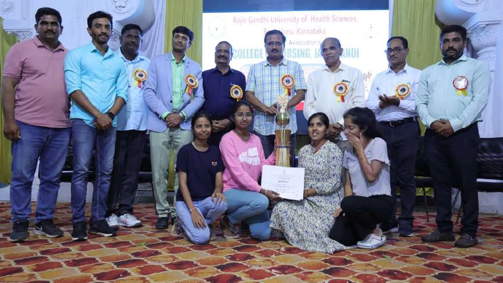 SVM Ayurvedic Medical College and RP Karadi Ayurvedic Hospital Ilkal women chess team receiving winners trophy and certificate from dignitaries at valedictory of RGUHS Kalaburagi Zone Chess Women Tournament 2024 at BLDEAS College of Nursing Jamkhandi Darbar Hall August 24 2024