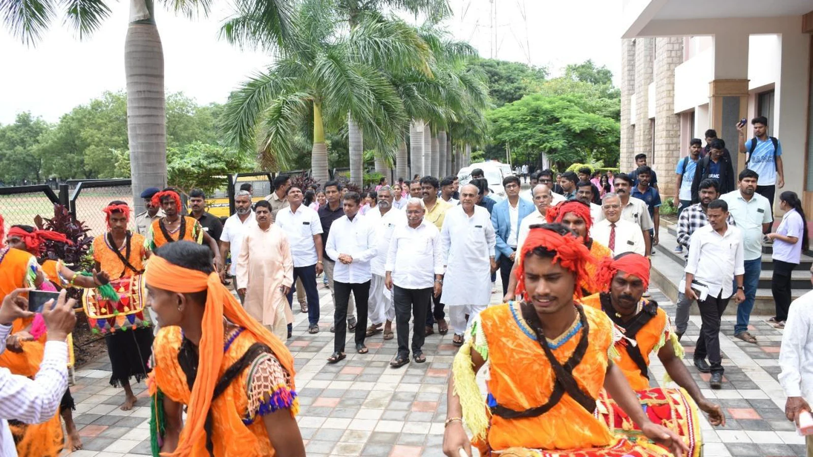 VIP procession with folk artists in traditional orange costumes welcoming Shri R B Timmapur Minister of Excise and other dignitaries at RGUHS Kabaddi Men Inter Zone and Women Single Zone Tournament cum Selection Trials 2025 hosted by BLDEA College of Nursing Jamkhandi