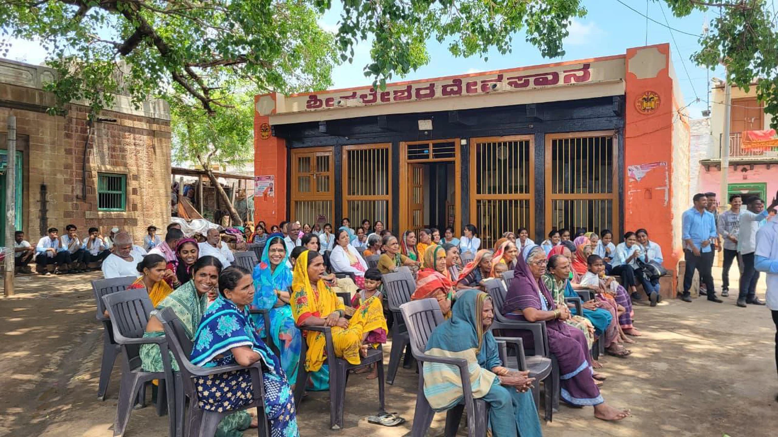 Large audience of Kakanwadi Village community members seated on chairs in front of building attending Drug Addiction Awareness Role Play organised by Seventh Semester BSc Nursing students BLDEA College of Nursing Jamkhandi June 2026
