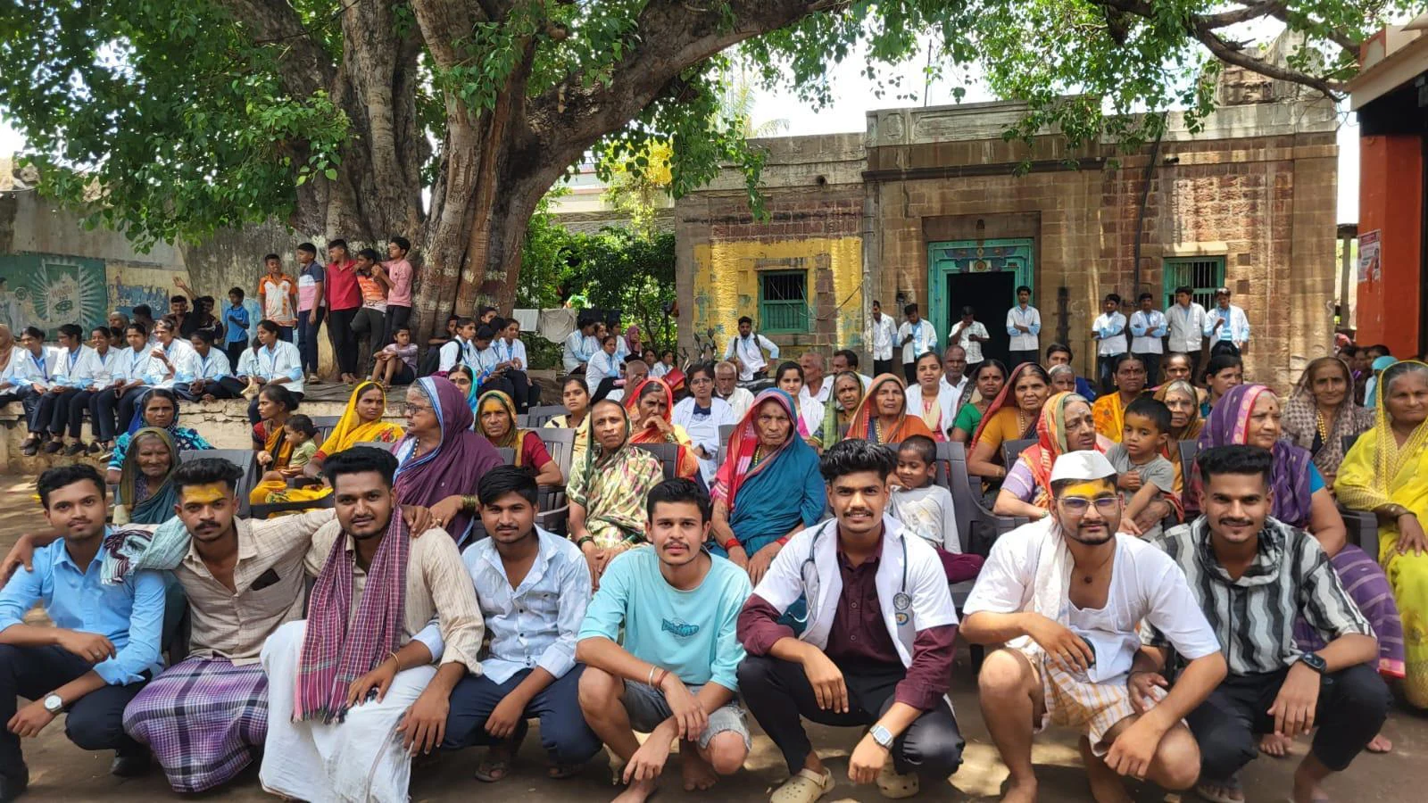Seventh Semester BSc Nursing students BLDEA College of Nursing Jamkhandi seated in front row with large gathering of Kakanwadi Village community members behind during Drug Addiction Awareness Role Play activity June 2026