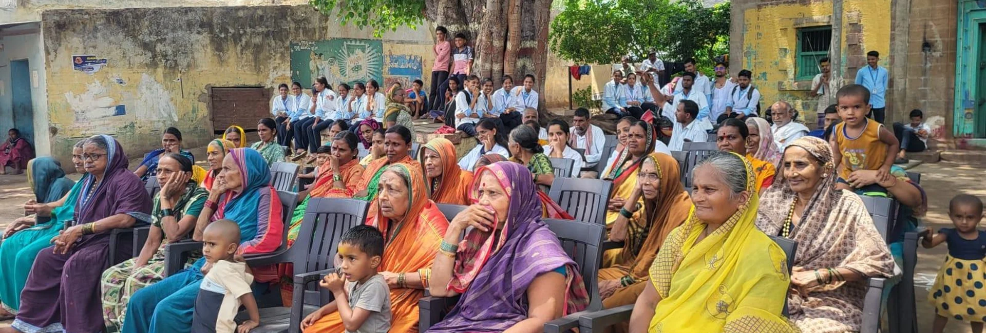 Fifth Semester BSc Nursing students BLDEA College of Nursing Jamkhandi with Kakanwadi Village community members gathered outdoors under large tree for Tobacco and Alcohol Prevention Role Play Community Health Nursing activity June 2026