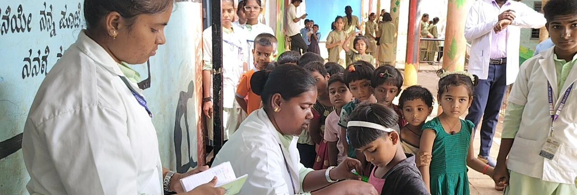 Nursing student doing mid-upper arm circumference measurement on a child at Government Primary School Mareguddi during School Health Program organized by final year BSc Nursing students BLDEAS College of Nursing Jamkhandi under guidance of Dr Veerabhadrappa Mendagudli Principal June 13 2025
