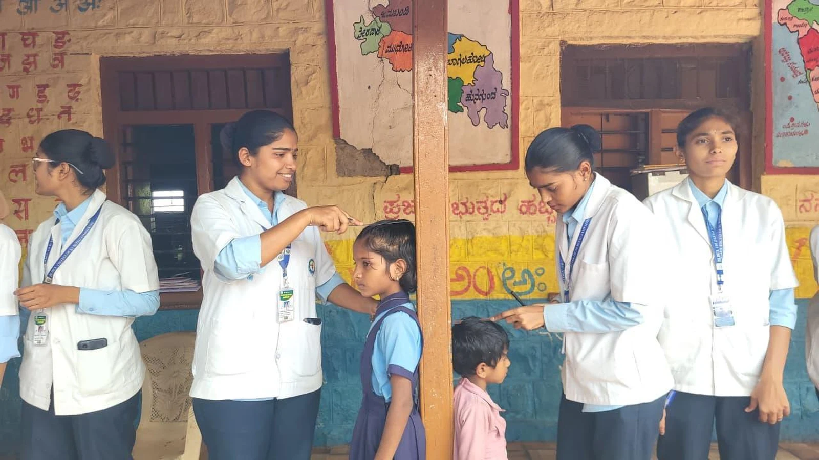 Fifth Semester BSc Nursing students BLDEA College of Nursing Jamkhandi measuring height of school children during health screening assessment at Government Primary School Kakanwadi School Health Programme June 2026
