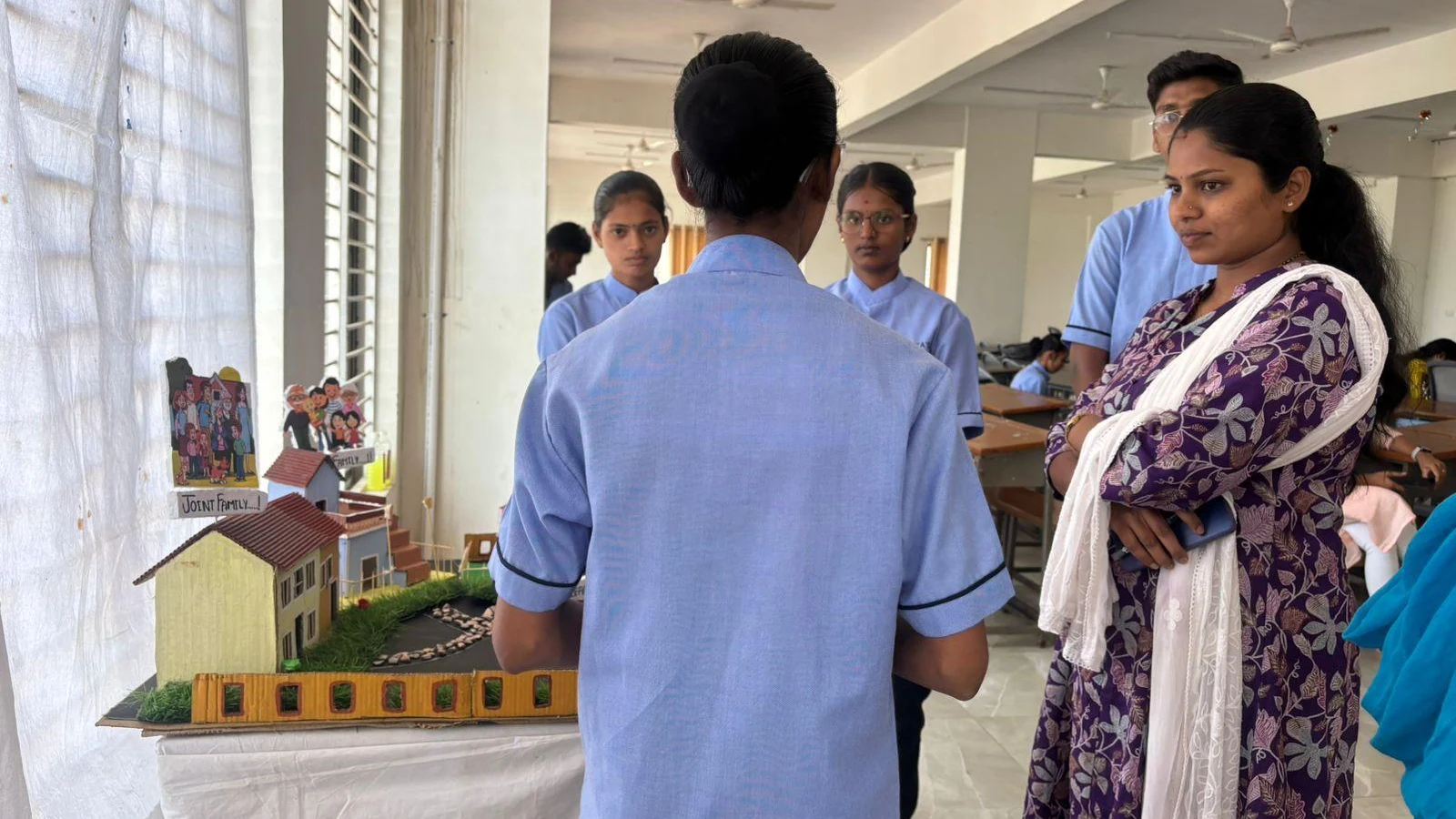 Student presenting community model to faculty during Sociology Psychology Model Exhibition – BLDEA College of Nursing Jamkhandi