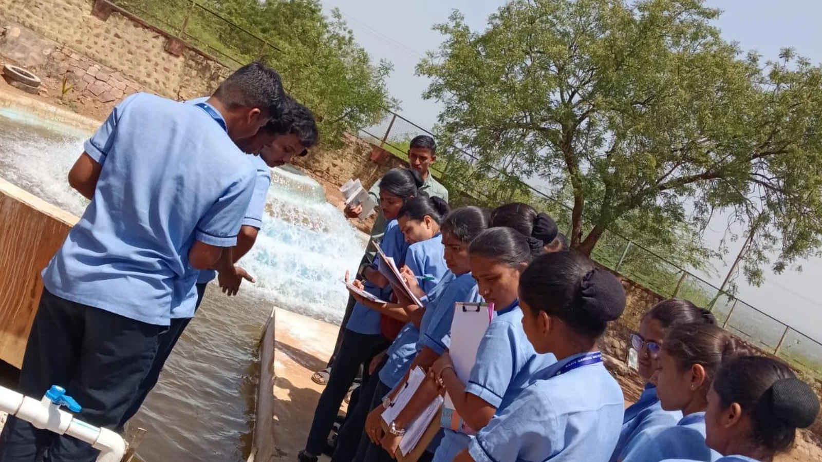 Nursing students and instructor at water treatment channel with notepads at Municipal Water Purification Plant Jamkhandi