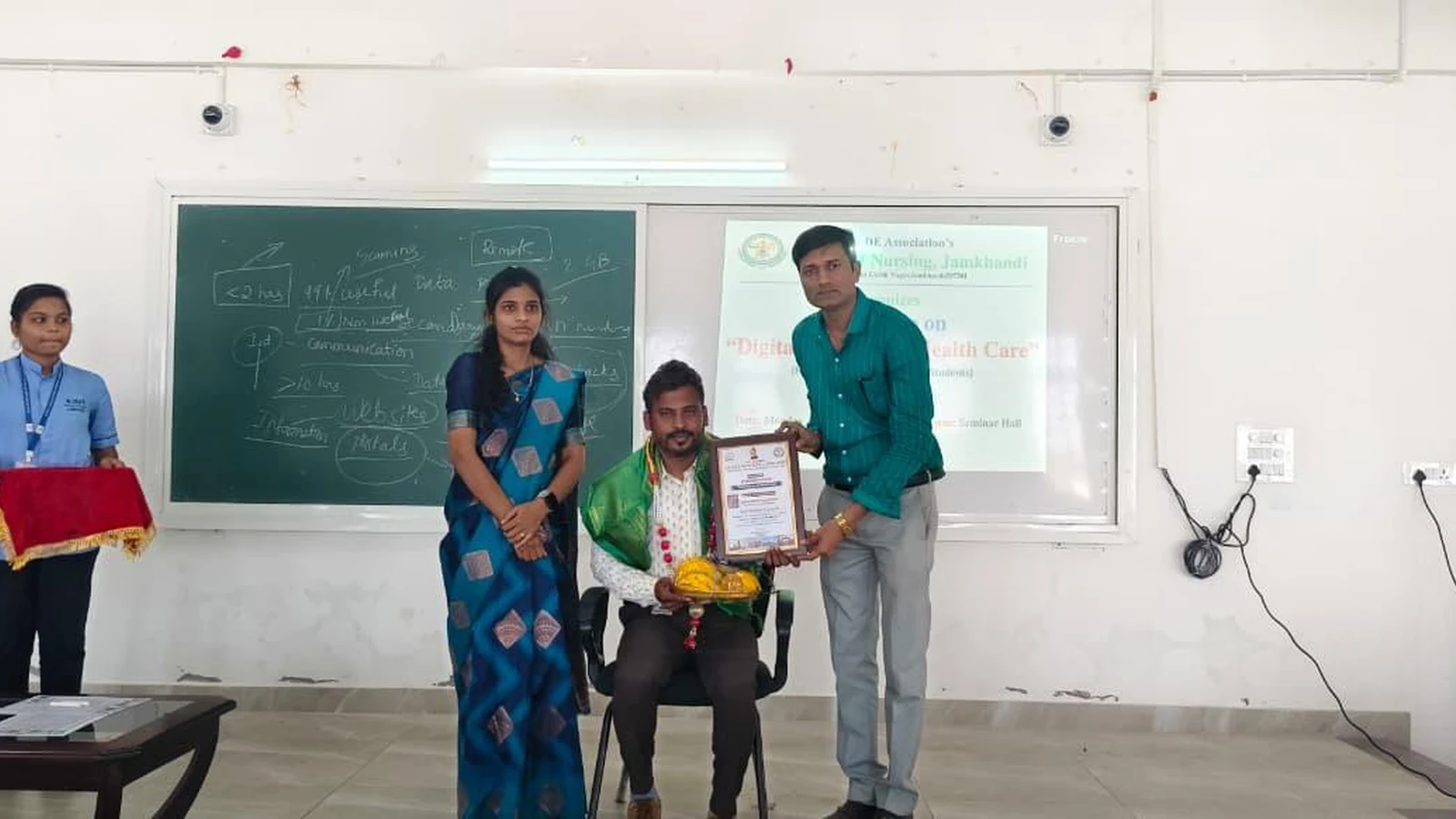 Faculty members felicitating resource person with certificate of appreciation and memento at Workshop on Digital Literacy for Health Care at BLDEA College of Nursing Jamkhandi with workshop banner on projector screen November 10 2025