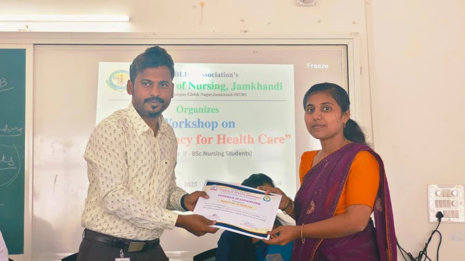 Faculty member presenting participation certificate to Second Semester BSc Nursing student at Workshop on Digital Literacy for Health Care at BLDEA College of Nursing Jamkhandi with workshop banner on projector screen November 10 2025