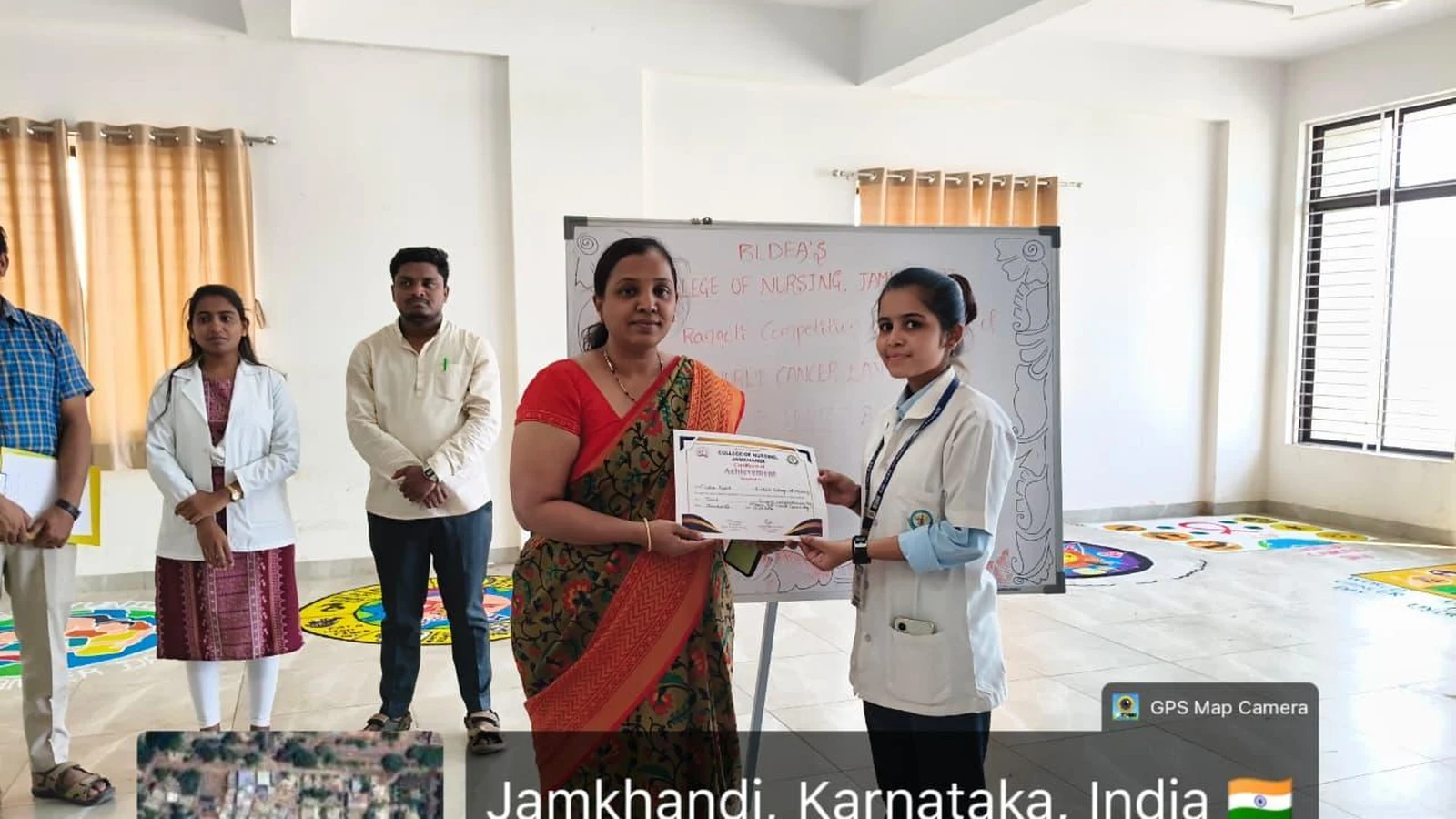 Dr. Sujata Biradar Assistant Professor BLDEA Pharmacy College Jamkhandi presenting winner certificate to student at World Cancer Day Rangoli Competition prize distribution on 6 February 2026